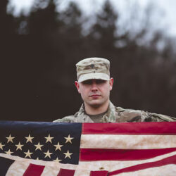 shallow-focus-shot-american-soldier-holding-american-flag_181624-20870